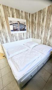 a white bed in a room with a wooden wall at Lust auf Meer - Ferienappartement in Cuxhaven