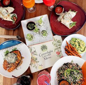 a wooden table with plates of food and drinks at Greenlight Fisherman's Village Resort & Café in Koh Samui 