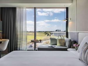 a bedroom with a bed and a couch and a large window at Pullman Auckland Airport in Auckland