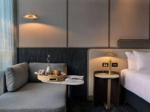 a room with a bed and a chair and a table at Pullman Auckland Airport in Auckland