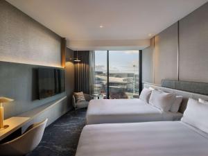 a hotel room with two beds and a window at Pullman Auckland Airport in Auckland