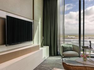 a living room with a large flat screen tv at Pullman Auckland Airport in Auckland