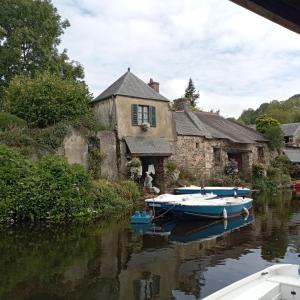 two boats are docked in front of a house at Cottage de charme en pierres à 25 mn de la côte de Granit rose in Bégard