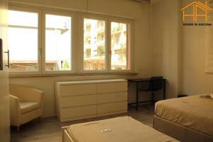a bedroom with two beds and a chair and windows at CarloAlberto23- Rooms by Homes in Ancona in Ancona