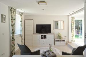 a living room with a flat screen tv on a cabinet at Romantic Greenhouse in Syke