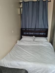 a bed in a bedroom with a window with white sheets at Nashville Homes in Ongata Rongai 