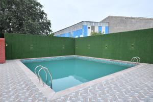 una piscina frente a una valla verde en Stamps by Eight Continents, Jodhpur, en Jodhpur