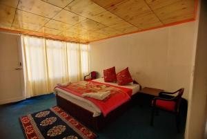 a bedroom with a bed with red pillows on it at Peace Cottages Pangong Ladakh by LexStays in Meruk