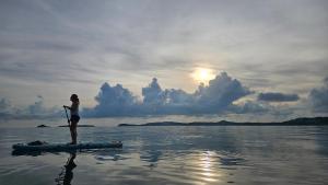 a woman standing on a paddle board in the water at Greenlight Fisherman's Village Resort & Café in Koh Samui 