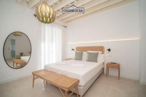 a white bedroom with a bed and a mirror at Sanlucar Centro - Apartamento 1 in Sanlúcar de Barrameda