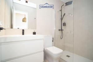 a white bathroom with a toilet and a sink at Sanlucar Centro - Apartamento 1 in Sanlúcar de Barrameda +12 photos