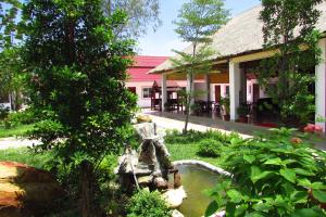 a garden with a fountain in front of a building at Manita Anna Guesthouse Jullyanna before in Sihanoukville
