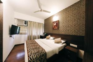 a hotel room with a bed and a flat screen tv at Hotel Maharana Inn Chembur in Mumbai +93 photos