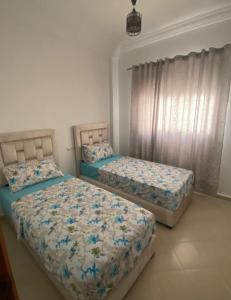a bedroom with two beds and a window at Résidence el fassi in Fès +3 photos