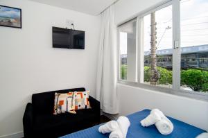 a bedroom with a bed and a chair and a window at Na rua do Balneário Shopping/Rodoviaria HK4532 in Balneário Camboriú