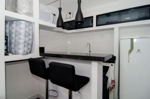 a kitchen with two black chairs and a counter at Na rua do Balneário Shopping/Rodoviaria HK4532 in Balneário Camboriú +3 photos