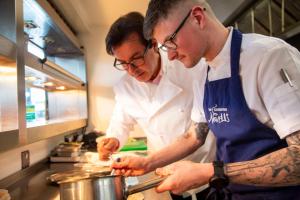 two chefs preparing food in a kitchen at AC Hotel by Marriott Belfast in Belfast