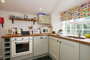 a kitchen with white cabinets and a sink at Finest Retreats - Old Lanvean Cottage in Saint Mawgan