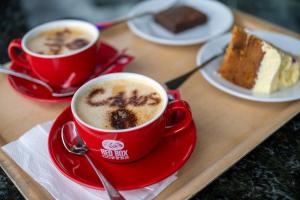 two cups of coffee on a tray with a piece of cake at Loch Ness Drumnadrochit Hotel in Drumnadrochit