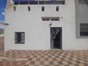 a white building with a door and a checkered floor at appartement Cristiana 6 Midoun in Midoun
