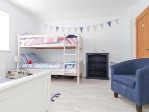 a bedroom with a bunk bed and a blue chair at The White House in Pwllheli