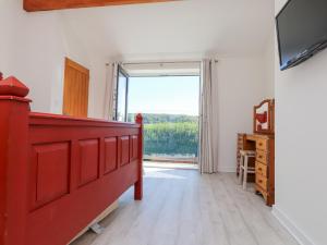 a room with a red bed and a large window at The White House in Pwllheli