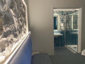 Un dormitorio con un baño con una pared de roca. en Cinquestelle Albergo del centro storico, en Palinuro 119 fotos más