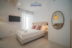 Un dormitorio con una cama blanca y un espejo. en Sanlucar Centro - Apartamento 2, en Sanlúcar de Barrameda