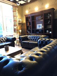 a living room with black leather couches and a table at Le Soyeureux Holiday Cottage Villa Spa in Spa