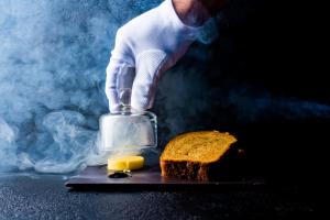 a person holding a block of butter and a piece of bread at Plas Dinas Country House in Caernarfon