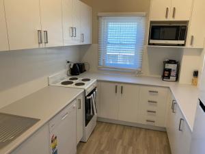 a kitchen with white cabinets and a stove top oven at Dalton Street Bungalow in Orange +6 photos