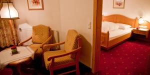 a hotel room with a bed and two chairs and a table at Appartement & Aparthotel Stern in Imst