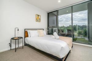 een slaapkamer met een groot bed en grote ramen bij Stylish 2BR Apt 5 mins to Canberra Hospital - Hosted by Canstay in Phillip