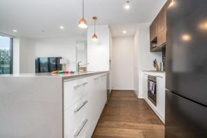 een keuken met witte kasten en een houten vloer bij Stylish 2BR Apt 5 mins to Canberra Hospital - Hosted by Canstay in Phillip