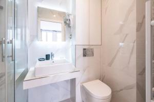 une salle de bain blanche avec un lavabo et des toilettes dans l'établissement Luxurious Apartment with Stylish Design and Comfort - 104, à Paris 9 autres photos