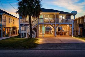 a large house with a balcony and a palm tree at A Boardwalk Away in Myrtle Beach