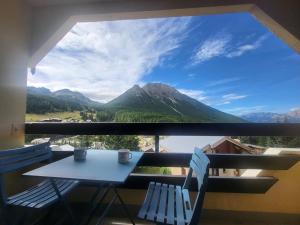 a table and chairs on a balcony with a view of mountains at Studio ensoleillé avec balcon au centre de Montgenèvre, proche commodités et pistes - FR-1-266-128 in Montgenèvre