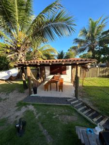 a wooden pergola with a table and a bench at Vila Santa Fé Caraíva in Caraíva +12 photos