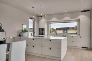 a kitchen with white cabinets and a large window at Feriested ved Strand & svaberg in Kristiansand