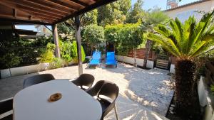 a patio with a table and chairs and a palm tree at Manors Seaside 2BR House 100m from the Beach & Free Parking in Meneou