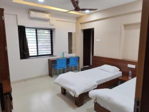 a room with two beds and a table with blue chairs at DatsunG Studios Near Pune Airport in Pune +28 photos