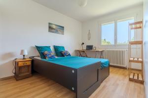 1 dormitorio con cama con sábanas azules y escritorio en Le Casselardit -T4 proche Hôpital - Clim - Balcon, en Toulouse