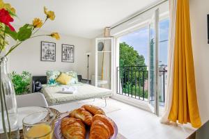 a room with a balcony with a table with croissants at COSYHOME - Studio Familial Confortable - Paris - CDG - Parking privé in Aulnay-sous-Bois