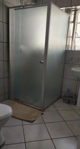 a glass shower door in a bathroom with a toilet at Brits Contractors Accommodation in Brits