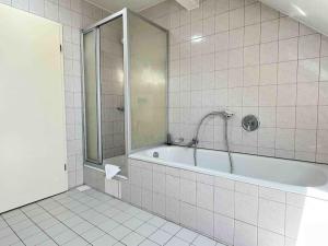 ein weiß gefliestes Bad mit einer Badewanne und einer Dusche in der Unterkunft SAD403 - Geräumig eingerichtete Monteurwohnung in Schwandorf in Bayern + 2 Fotos
