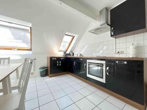 eine Küche mit schwarzen Geräten und weißem Fliesenboden in der Unterkunft SAD403 - Geräumig eingerichtete Monteurwohnung in Schwandorf in Bayern