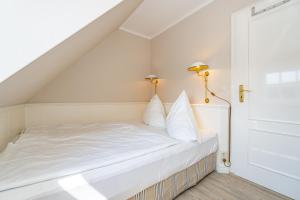 une chambre avec un lit blanc et deux lampes dans l'établissement Roseneck App 6, à Tinnum