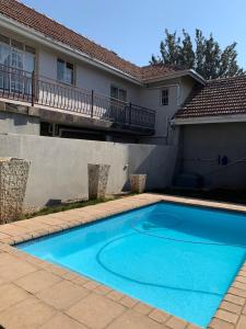 a blue swimming pool in front of a house at Home Away from Home in Roodepoort