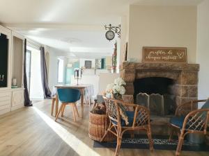 a living room with a fireplace and a table and chairs at Le Clos Gagné in Bais