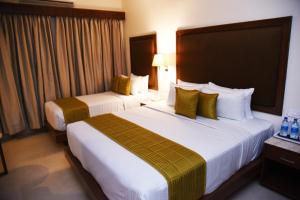 2 letti in camera d'albergo con cuscini gialli di Hotel Rameswaram Grand a Rāmeswaram